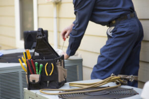 An air conditioner Technician from R.D. Davis Heating & Air Conditioning services an oudoor unit as part of their work as HVAC contractors in Chatham IL