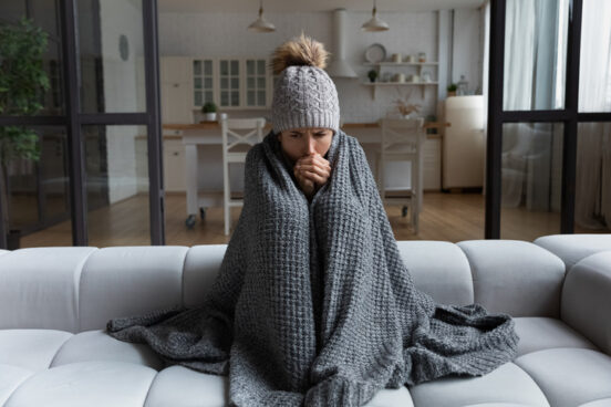 A woman sits on her couch trying to warm up before calling Heating Contractors Springfield IL trusts, R.D. Davis Heating & Air Conditioning