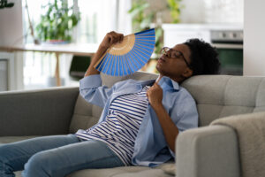 A woman fans herself in her home after calling R.D. Davis Heating & Air Conditioning for Air Conditioning Repair Rochester IL services